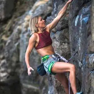 Female athlete rock climbing outdoors, emphasizing the importance of hydration and performance