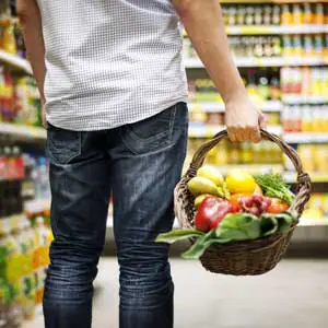 Person holding a basket of fresh produce in a grocery store, representing Boulder Salt's connection with natural and health-conscious food choices