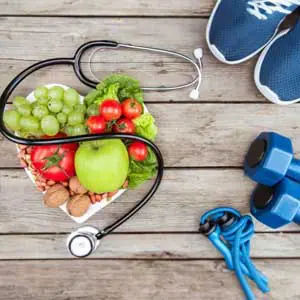 Basket of fresh fruits and vegetables with a stethoscope and weights, illustrating Boulder Salt's support for a balanced and healthy diet.